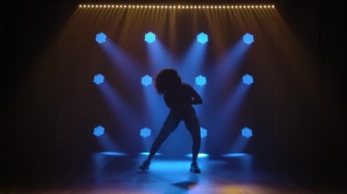 Jazz funk eşofmanlı genç bir kız tarafından icra edildi. Yavaş çekimde mavi ışıkları olan karanlık bir stüdyo arka planında siluet..