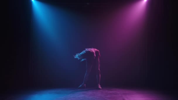 Mädchen mit welligem Haar tanzen Jazz-Funk in Zeitlupe. Eine Silhouette erscheint auf einem hinterleuchteten rauchigen Hintergrund. — Stockvideo