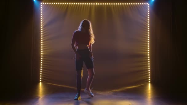 Moderne belle fille dansant jazz funk dans un studio sombre avec contre-jour. Silhouette au ralenti. — Video