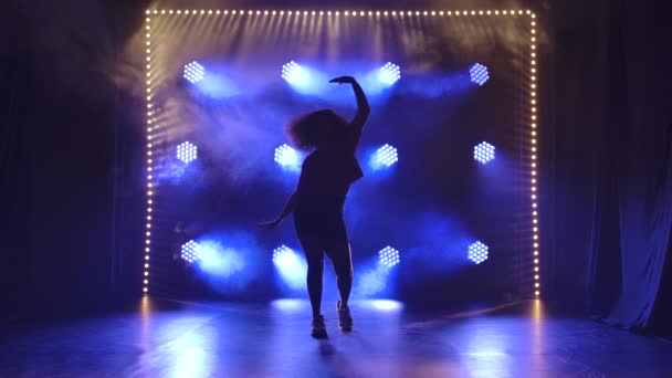 Young girl dancing jazz funk in the studio in slow motion. Silhouette against the background of blue lights. — Stock Video