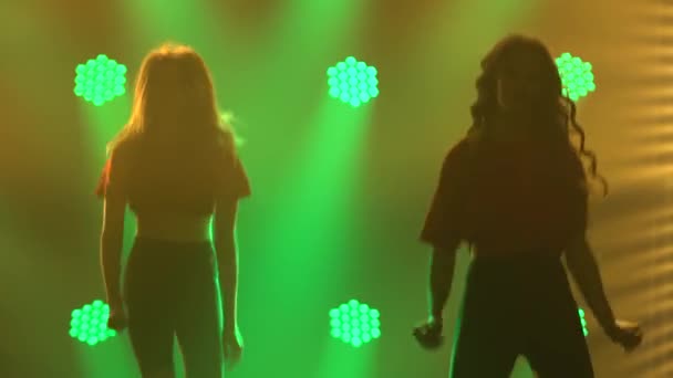 Uma equipe de garotas dançando jazz-funk em um estúdio escuro com luzes de néon. Silhuetas. Fechar. — Vídeo de Stock
