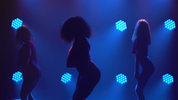 Drie schattige meisjes dansen actief jazz funk in de schijnwerpers. Silhouetten van dansers close-up. — Stockvideo