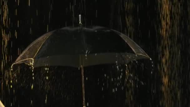 Lluvia en cámara lenta goteando paraguas negro. Disparo de cerca en un estudio con retroiluminación oscura. — Vídeos de Stock