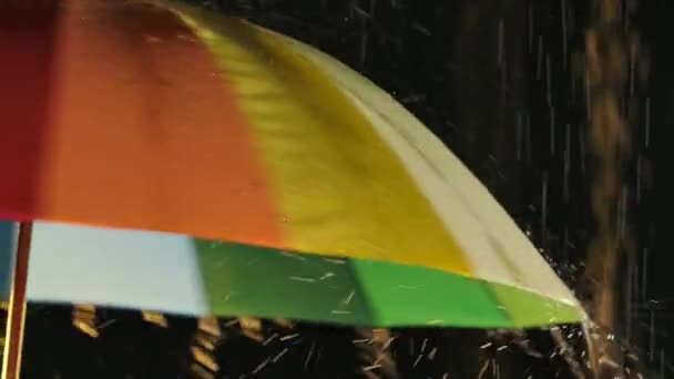 Радужный зонтик, мокрый от дождевых вихрей в закрытой студии на черном фоне. Закрывай. Медленное движение. — стоковое видео