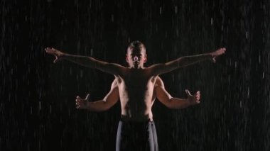 İki profesyonel erkek sanatçı tarafından yapılan akrobatik yağmur gösterisi. Karanlık bir stüdyoda suyun yüzeyinde çekilmiş. Ağır çekim. Kapat..