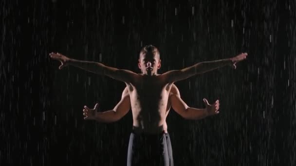 Acrobatische show in de regen uitgevoerd door twee professionele mannelijke artiesten. Schot op het wateroppervlak in een donkere studio. Langzame beweging. Sluiten.. — Stockvideo