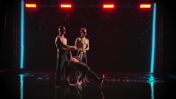 男人在雨中表演杂技特技.3名男性杂技演员的专业表演。红色霓虹灯的黑色背景。慢动作. — 图库视频影像