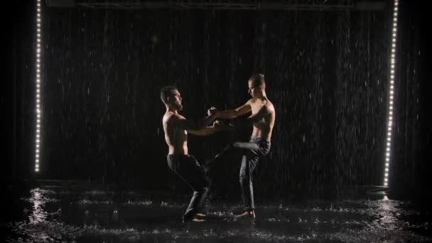 Un grupo de gimnastas acrobáticos realizan ejercicios acrobáticos complejos mientras están de pie en la superficie del agua bajo la lluvia. Movimiento lento. — Vídeos de Stock