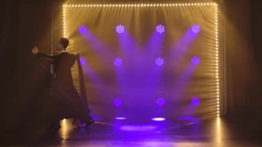 Bir çift profesyonel balo dansçısı spot ışıkları altında karanlık bir stüdyoda vals yapıyor. Yavaş çekim.