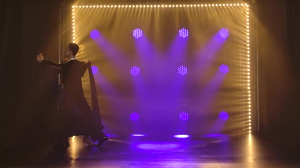 Ett par professionella balsalsdansare som dansar vals i en mörk studio i rampljuset. Långsamma rörelser. — Stockvideo