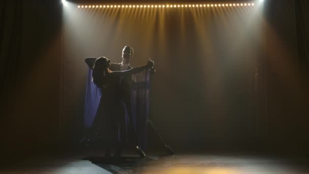 Siluet dari pasangan menari berlatih waltz di sebuah studio asap gelap dengan cahaya latar. Gerakan lambat. — Stok Video