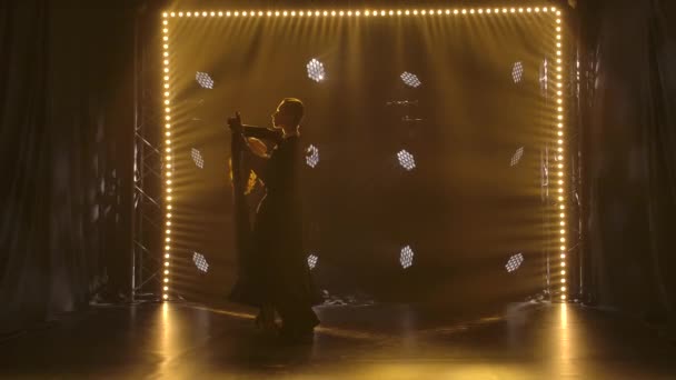 Młoda para elegancko tańcząca walca i płynnie poruszająca się w studio z neonowymi reflektorami. Sylwetki. Zwolniony ruch. — Wideo stockowe