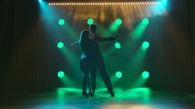 Bir çift profesyonel dansçı Latin Amerika balo salonu dansları rumba, cha cha, samba icra ediyor. Siluetler, yeşil ışıkları olan karanlık bir stüdyoda tutkuyla dans eden çiftler. Yavaş çekim.