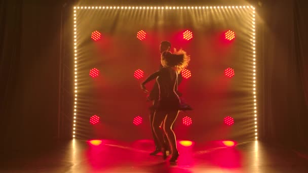 Jong mooi koppel dansend sensueel dans cha cha cha cha. Silhouetten van dansers in een donkere studio met rode spots. Langzame beweging. — Stockvideo