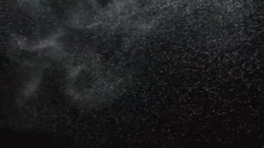 Bir toz parçacıkları bulutu siyah dumanlı arka planda türbülanslı bir rüzgarla dinamik bir şekilde yüzer. Kapatın. Yavaş çekim.