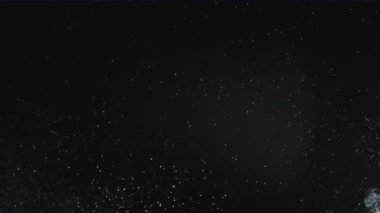 Siyah dumanlı arka planda ince beyaz tozlar yayıldı. Kapatın. Yavaş çekim.