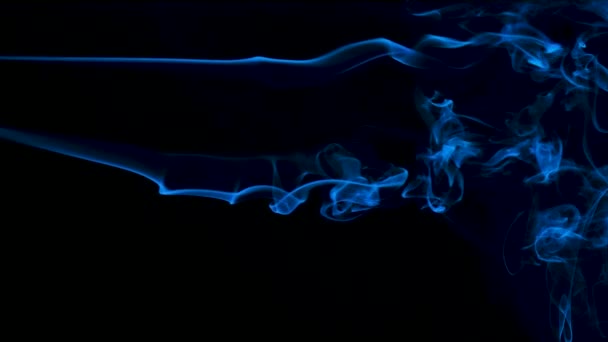 Eine horizontale Rauchfahne vor einem blau hinterleuchteten schwarzen Hintergrund schafft abstrakte Linien. Aus nächster Nähe. Zeitlupe. — Stockvideo