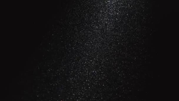 De petites particules de poussière brillantes volent dans l'air sur un fond noir. Fond abstrait d'animation de microparticules sous forme de fines poussières au ralenti. Gros plan. — Video