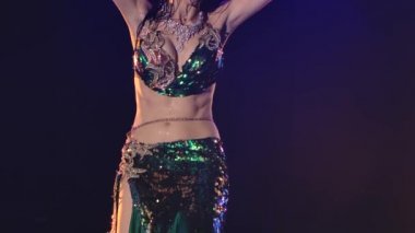 Yağmur damlaları içinde, doğulu bir dansçının ıslak, parlak gövdesi. Dans eden ve parlak elbiseler içinde kalçalarını sallayan bir kadın. Yavaş çekim.