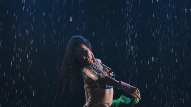Sexy orientalische Tänzerin genießt Bauchtanz unter den Regentropfen in einem dunklen Studio. Zeitlupe. Nahaufnahme.