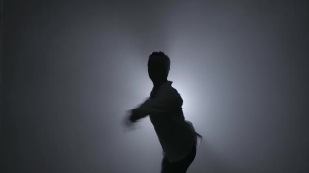 Una pirueta interpretada por un bailarín de ballet masculino actuando en un oscuro estudio ahumado. Siluetas en el centro de atención. Primer plano en cámara lenta. — Vídeos de Stock