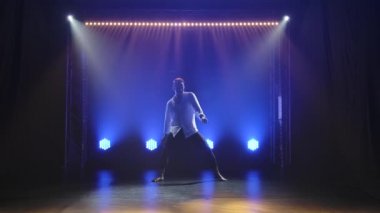 Çağdaş bale, modern koreografinin unsurlarını icra eden ve spot ışıklarına çıkan bir adam. Karanlık bir stüdyodaki erkek dansçının siluetleri. Yavaş çekim.