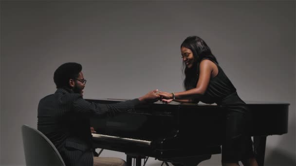 Mutlu genç Afrikalı Amerikalı çift siyah bir piyanonun yanında el ele tutuşup birbirlerine gülümsüyorlar. Sonunda, video bulanıklaşır. Ağır çekim. Kapat.. — Stok video