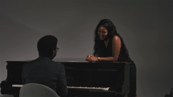 Vue de dos d'un jeune musicien afro-américain jouant du piano noir pour sa bien-aimée. Une femme heureuse sourit et aime la musique. Au ralenti. Gros plan. — Video