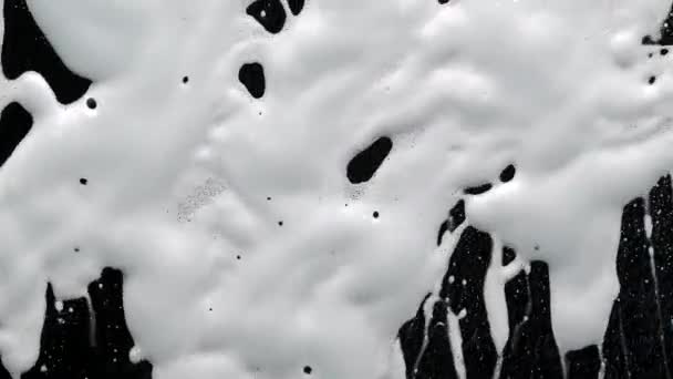 Le concept de nettoyage et de désinfection des surfaces des virus. Détergent savonneux sur verre. La mousse et l'eau s'égouttent sur un fond noir. Concept de protection Covid 19. — Video