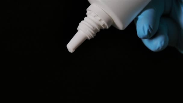 Les mains masculines dans des gants de protection pressent une bouteille de médicament nasal sur un fond noir. Prévention de la COVID 19 et de la propagation du coronavirus. Au ralenti. Gros plan. — Video