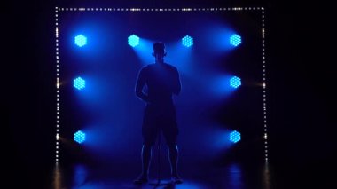 Mavi ışıkların arka planında dumandaki bir adamın silueti mikrofona şarkı söylüyor. Şarkıcılar geceleri stüdyoda solo performans sergilerler..