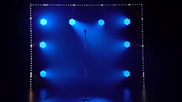 Silhuett av en konsert vintage mikrofon som står i en tom mörk studio med rök. En blå spotlight tänds och lyser upp på en krommikrofon. — Stockvideo