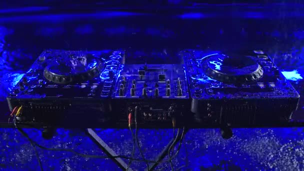 오디오 혼합 컨트롤러는 어두운 스튜디오에 있고 파란색 조명이 있습니다. DJ 도구가 쏟아지는 빗속에 있어요. 위에서 본 모습. 닫아. 느린 동작. — 비디오