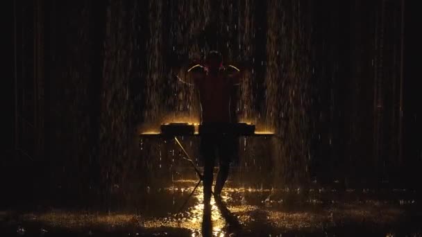 Un dj maschio dalla silhouette nuda suona musica dance elettronica sui giradischi e gode della pioggia in uno studio buio. Girare video su uno sfondo scuro al rallentatore. — Video Stock