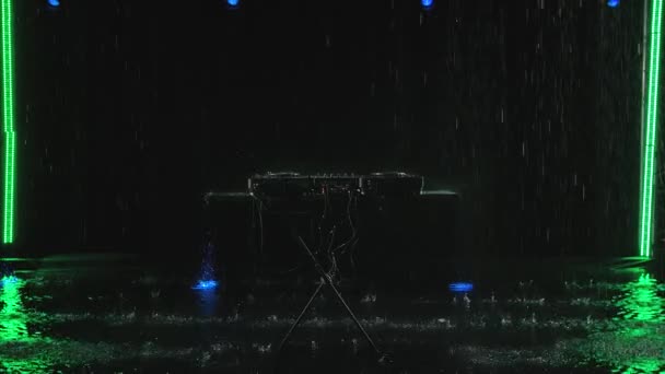 Club Discjockey Bühnenausstattung zum Abspielen von Partymusik. Professionelles Konzert-DJ-Plattenspieler-Gerät im Regen auf dem Hintergrund eines dunklen Studios mit Hintergrundbeleuchtung. Zeitlupe. — Stockvideo