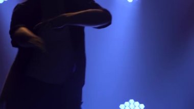 Balo dansçısı yavaş çekimde zarafetle salsa yapıyor. Bir adamın gövdesine yakın çekim. Siluet.