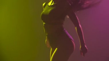 Stüdyoda arka planda dans eden yarı çıplak seksi kadın. Bir kadın dansçının vücudu. Yavaş çekim.