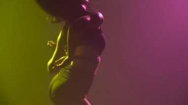 Stüdyoda arka planda dans eden yarı çıplak seksi kadın. Bir kadın dansçının vücudu. Yavaş çekim.