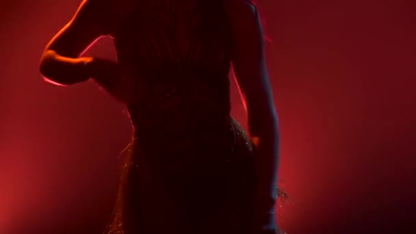 Twee dansers genieten van een salsa dans in een donkere studio met neonverlichting. Paar roteren hun heupen in slow motion close-up. Silhouetten. — Stockvideo