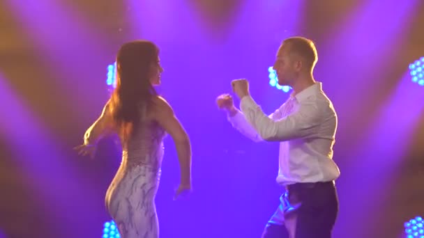 Ζευγάρι χορεύει παθιασμένα καυτό όμορφο χορό salsa. Νεαρός άντρας και γυναίκα χορεύουν στο στούντιο με φόντο τα λαμπερά μπλε φώτα. Κλείσε.. — Αρχείο Βίντεο
