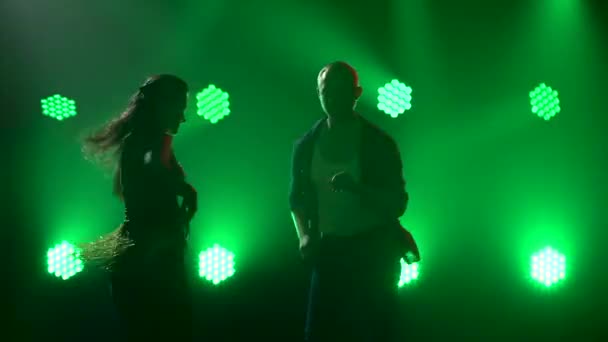 Dansers oefenen hobby 's en dansen salsa in een donkere studio. Silhouetten van dansende man en vrouw van dichtbij. Dynamische show van heldere veelkleurige neon lichten. — Stockvideo