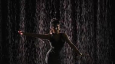 Şık mavi elbiseli bir dansçı Arjantin Flamenko 'sunun kışkırtıcı dansının unsurlarıyla dans ediyor. Yağmurda siyah arka planda dans eden bir kadın. Arkadan ışık geliyor. Ağır çekim, yakın çekim..