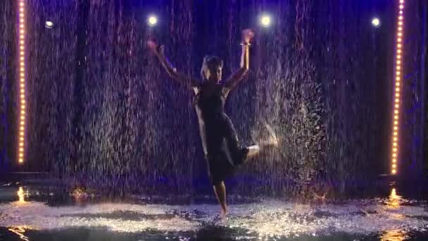 Flamenco argentino bajo la lluvia. Mujer atractiva disfruta de la danza creando un montón de spray con los pies. Fondo azul. En cámara lenta. Silueta. — Vídeos de Stock