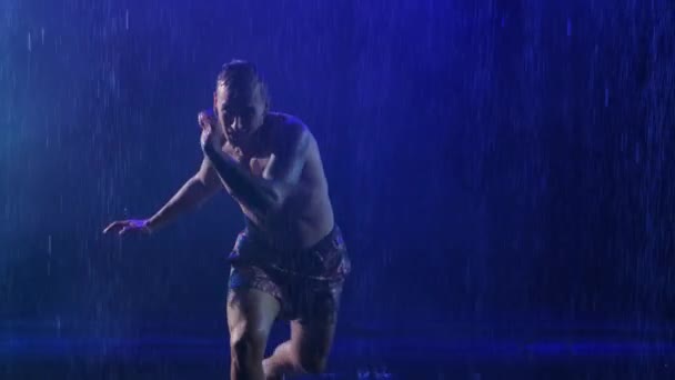 土砂降りの雨の中暗い煙スタジオでカポエイラを練習する男のシルエット。ダンスの要素を組み合わせた武道。スローモーションを閉じます. — ストック動画