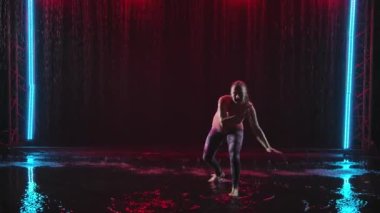 Formda bir dişinin silueti yağmurda karmaşık numaralar yapan ve çok fazla su sıçratan bir atlet-akrobat-capoeira 'dır. Sağlıklı yaşam tarzı, spor aşkı. Yavaş çekim.