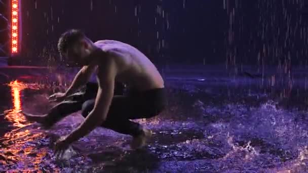 Silueta de un hombre que practica capoeira en un oscuro estudio ahumado bajo la lluvia. Un arte marcial que combina elementos de danza. Primer plano en cámara lenta. — Vídeos de Stock