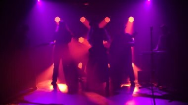 Şarkıcı bir rock grubunun performansında mikrofona duygusal olarak bağırır. Retro takım elbiseli bir kadın şarkı söyler ve İrlandalı şapkalı dört adam müzik enstrümanları çalar. Siluetler. Yavaş çekim.