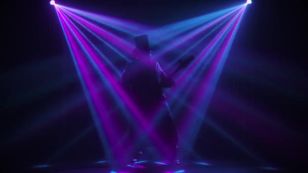 Aktywny muzyk emocjonalny grający na gitarze elektrycznej w ciemnym, zadymionym studio z dynamicznymi światłami. Sylwetka. Koncert na żywo. Zwolniony ruch. — Wideo stockowe