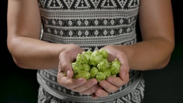 Primer plano de un joven está mostrando en cámara un montón de flores de lúpulo crudo biológico utilizado para la producción de cerveza de alta calidad en la cervecería artesanal ecológica cosechada en una temporada adecuada. — Vídeos de Stock