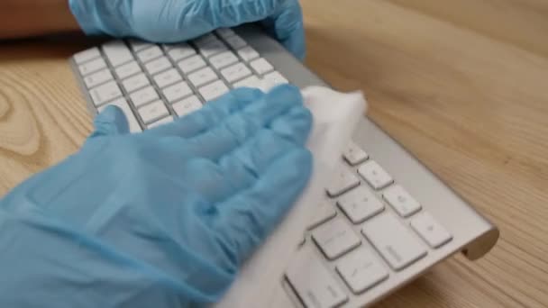 Las personas de la mano en el guante médico protector azul usando toallita húmeda y limpieza cuidadosamente teclado portátil en el lugar de trabajo. Medidas de prevención en el período de brote del coronavirus. De cerca. Movimiento lento. — Vídeos de Stock